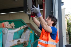 Worker at a waste container throwing away folders in a dumpster rental in Lott TX